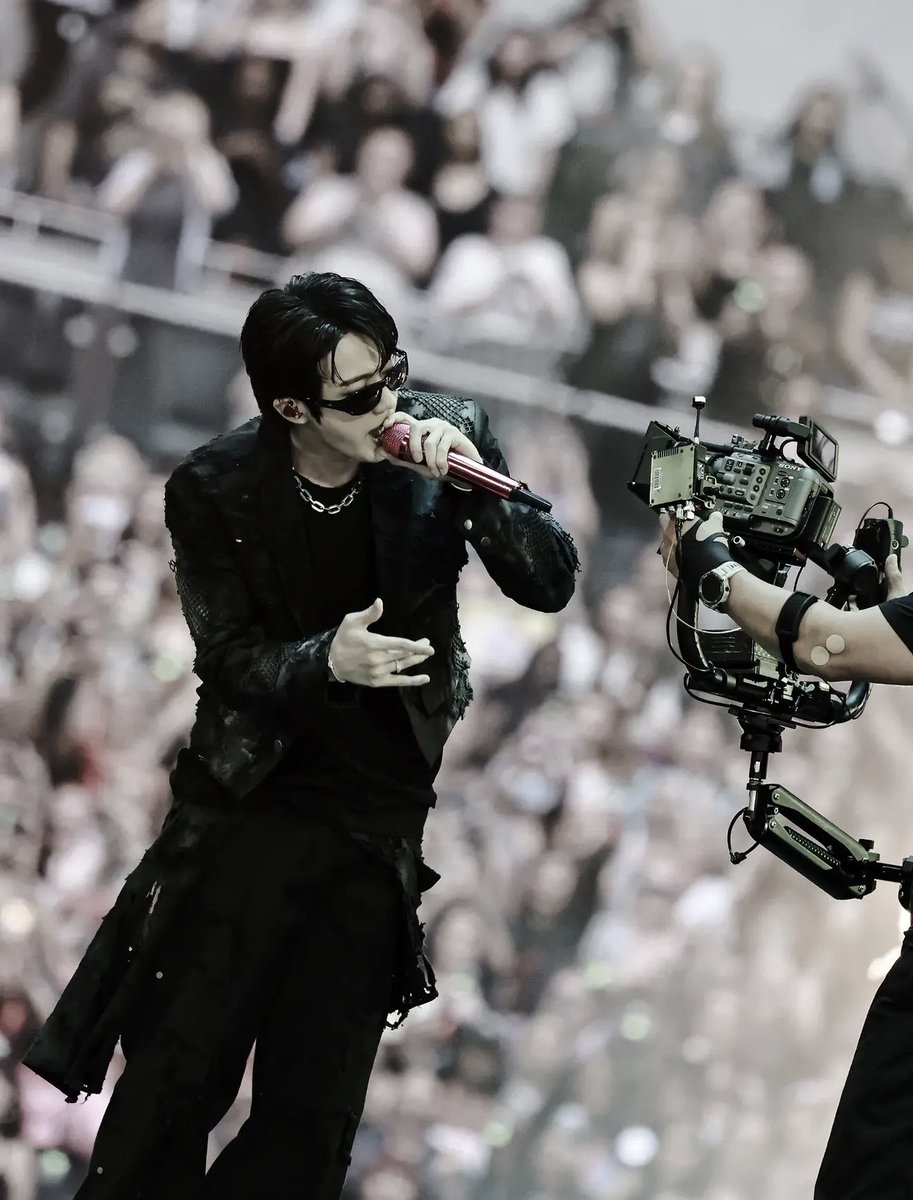 Jin performing on stage in a black rockstar look